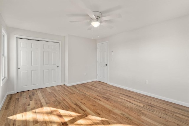 unfurnished bedroom with baseboards, ceiling fan, light wood-style floors, and a closet