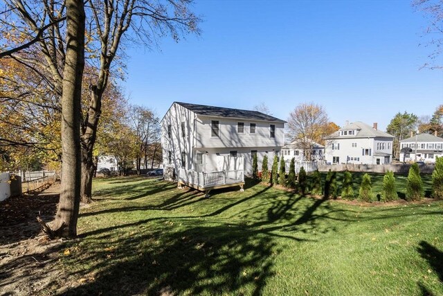 rear view of property with a lawn, a wooden deck, and fence