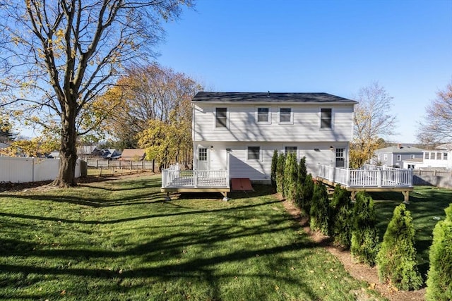 back of property with a deck, a yard, and fence