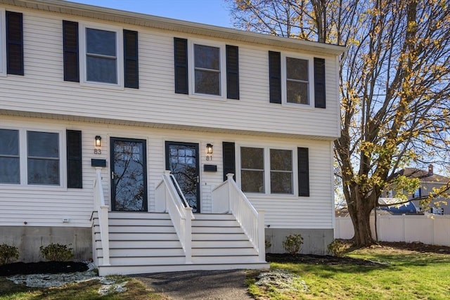 colonial inspired home with a front yard and fence