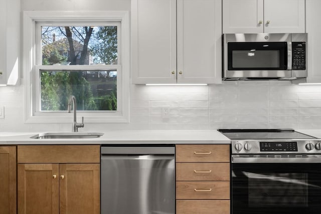 kitchen featuring appliances with stainless steel finishes, tasteful backsplash, light countertops, and a sink