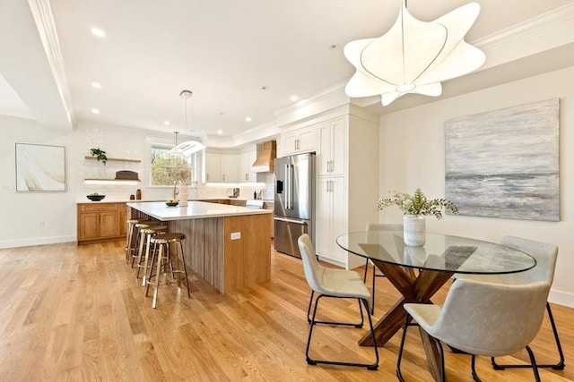 3 Colburn St Unit 1, Gloucester, MA 01930 - kitchen featuring high end fridge, premium range hood, a kitchen island, light countertops, and a kitchen breakfast bar