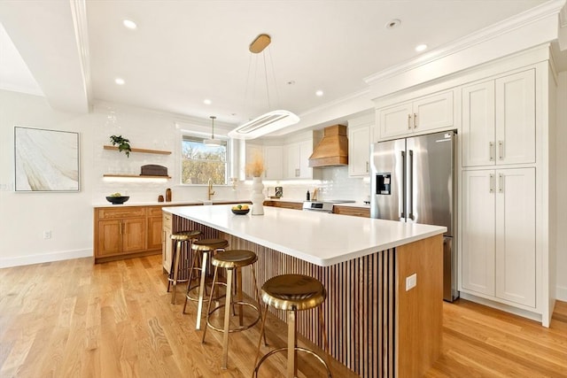 3 Colburn St Unit 1, Gloucester, MA 01930 - kitchen with custom exhaust hood, stainless steel appliances, a kitchen island, light wood finished floors, and a kitchen bar