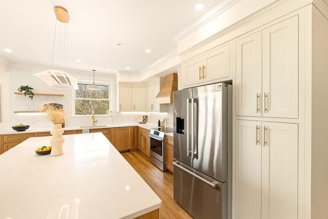 3 Colburn St Unit 1, Gloucester, MA 01930 - kitchen featuring appliances with stainless steel finishes, premium range hood, light wood finished floors, crown molding, and decorative light fixtures