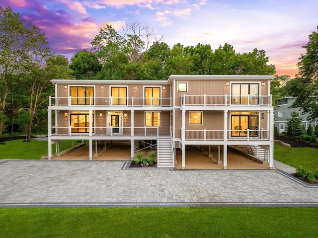 3 Colburn St Unit 1, Gloucester, MA 01930 - back of property at dusk with a balcony, stairs, a lawn, and driveway