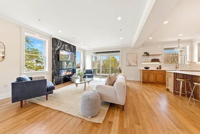 3 Colburn St Unit 1, Gloucester, MA 01930 - living room featuring plenty of natural light, light wood-style floors, crown molding, a premium fireplace, and recessed lighting