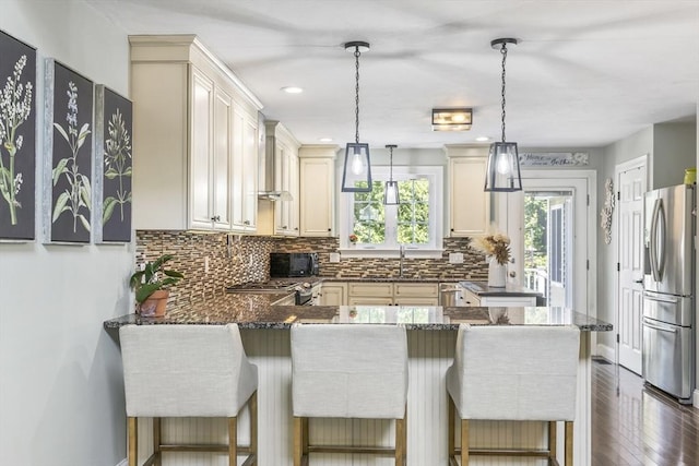 1 Woodland Ct Unit B, Milford, MA 01757 - kitchen with appliances with stainless steel finishes, a peninsula, backsplash, dark wood-style floors, and pendant lighting