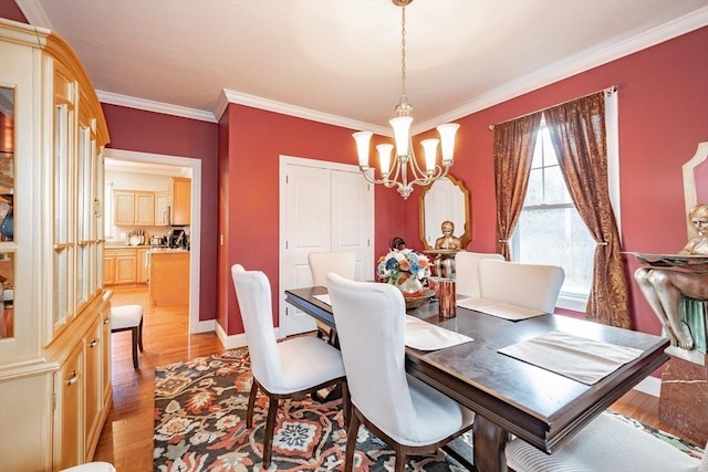 dining space with crown molding, a chandelier, and light wood-type flooring