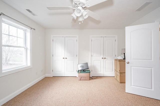 unfurnished bedroom with multiple windows, ceiling fan, and light colored carpet