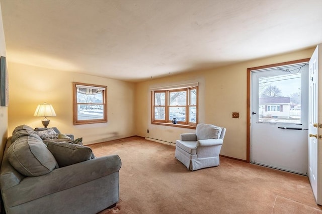 living area with a baseboard heating unit and light colored carpet