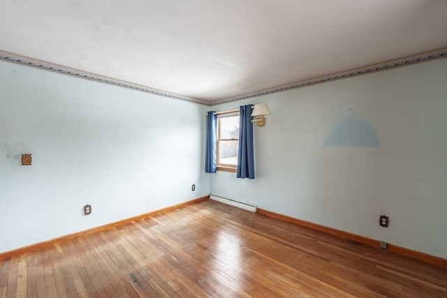 unfurnished room featuring baseboard heating, light wood-type flooring, and baseboards