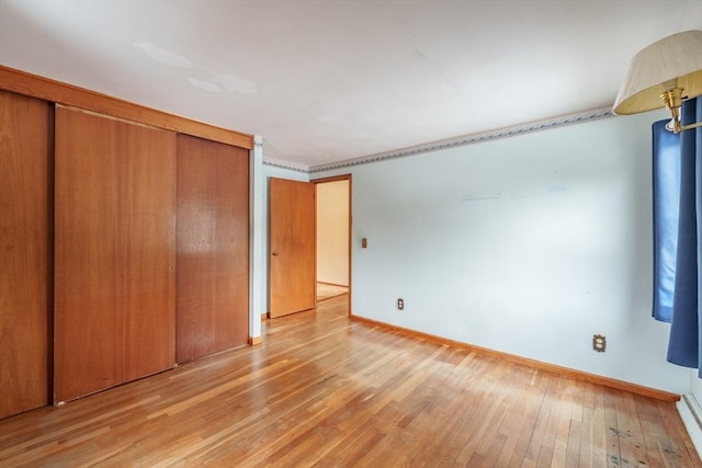 unfurnished bedroom with light wood-type flooring, a closet, and baseboards