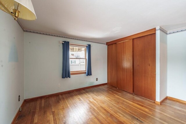 unfurnished bedroom featuring light wood-type flooring, a closet, and baseboards