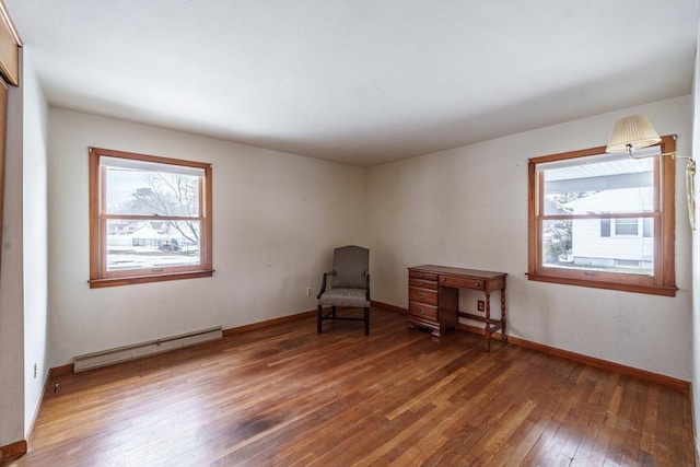 unfurnished room featuring baseboards, baseboard heating, and hardwood / wood-style flooring