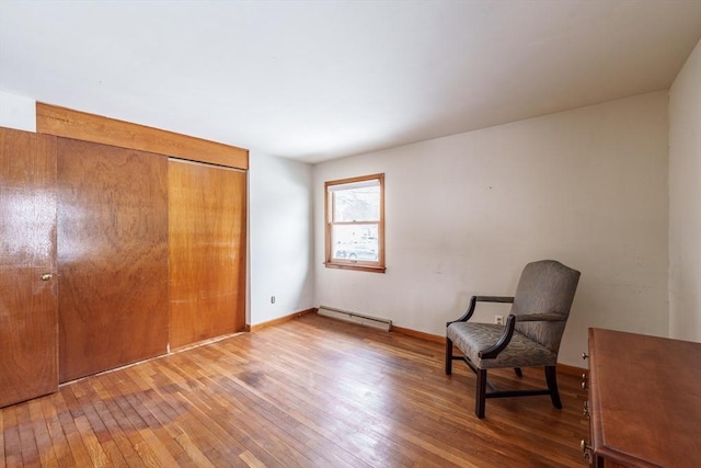 unfurnished room featuring a baseboard radiator, wood-type flooring, and baseboards