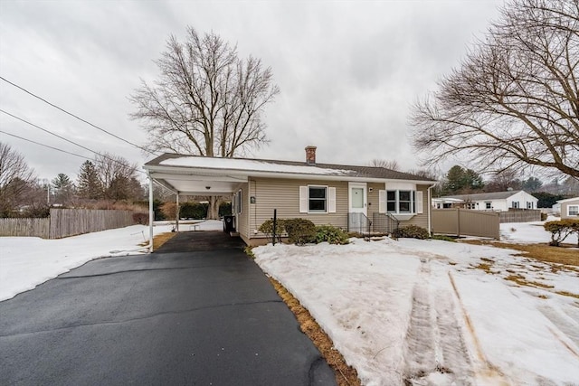 view of front of property featuring a carport, aphalt driveway, a chimney, and fence