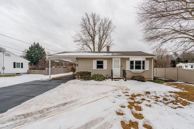 view of front of property with driveway, entry steps, a chimney, fence, and a carport