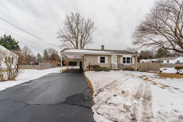 view of front facade with a chimney, fence, aphalt driveway, and a carport