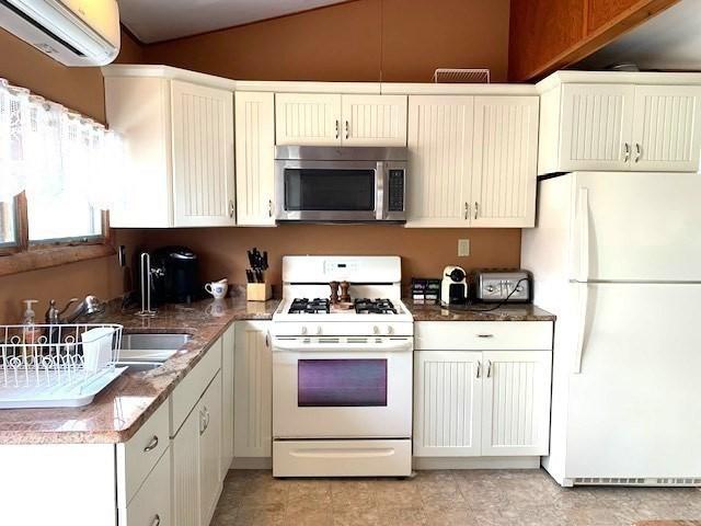 114 Long Bch, Rockport, MA 01966 - kitchen with white appliances, an AC wall unit, lofted ceiling, a sink, and white cabinets