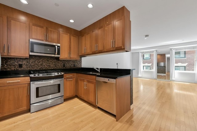 kitchen featuring light wood-type flooring, stainless steel appliances, backsplash, and sink