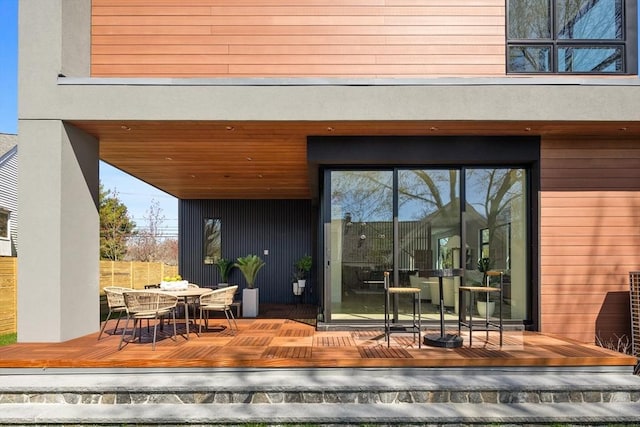 view of exterior entry featuring outdoor dining area and a wooden deck