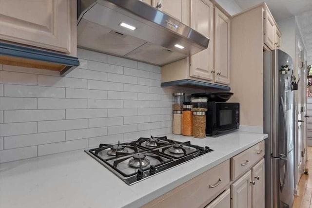 8 Deer Path Unit 8, Hudson, MA 01749 - kitchen with under cabinet range hood, freestanding refrigerator, gas cooktop, light countertops, and backsplash