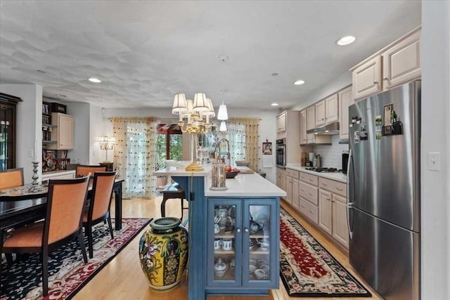 8 Deer Path Unit 8, Hudson, MA 01749 - kitchen with appliances with stainless steel finishes, light countertops, light wood-style floors, a chandelier, and under cabinet range hood