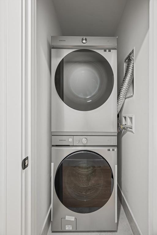 laundry area featuring stacked washer / drying machine and light tile patterned floors