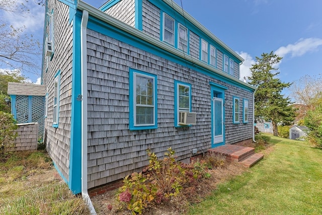 view of side of home with a lawn, cooling unit, and a shed