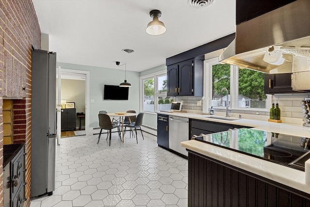 kitchen featuring freestanding refrigerator, light countertops, backsplash, dishwasher, and hanging light fixtures