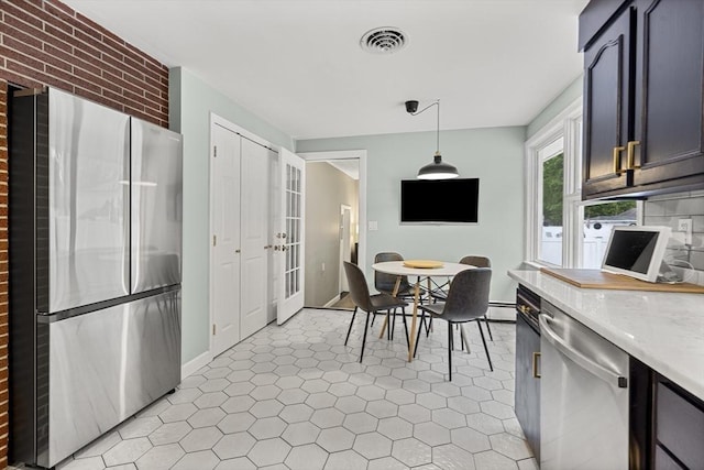 kitchen with stainless steel appliances, light countertops, pendant lighting, french doors, and brick wall