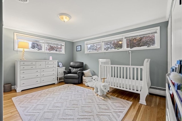 bedroom featuring ornamental molding, light wood-style floors, a nursery area, and baseboards