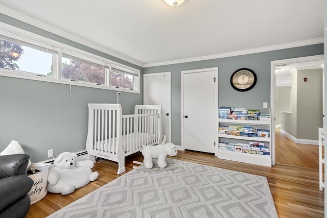bedroom with crown molding, wood finished floors, baseboards, and multiple closets