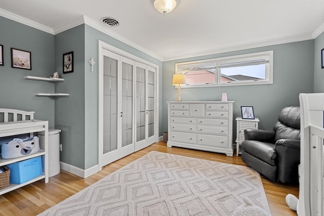 bedroom with light wood-type flooring, ornamental molding, baseboards, and a closet