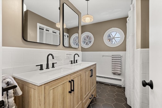full bath with a baseboard heating unit, tile walls, wainscoting, double vanity, and tile patterned flooring