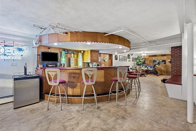 indoor dry bar featuring a baseboard heating unit and stainless steel fridge