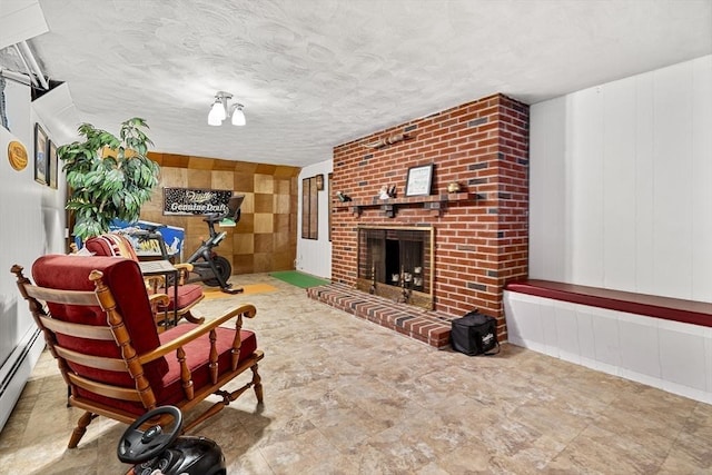 living room featuring a fireplace, baseboard heating, a decorative wall, and a textured ceiling
