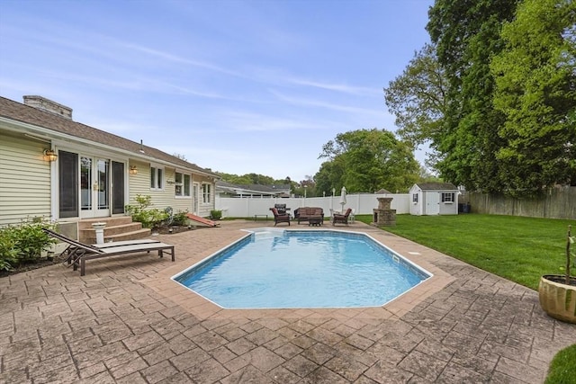 view of swimming pool featuring french doors, a patio, a storage shed, and an outbuilding
