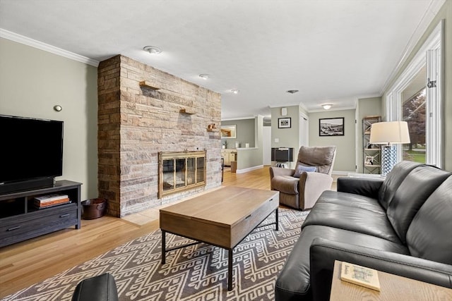 living area with ornamental molding, wood finished floors, a fireplace, and baseboards