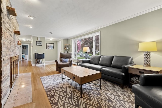 living area featuring light wood finished floors, a fireplace, baseboards, and crown molding