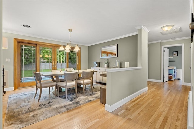 dining space with light wood-type flooring, ornamental molding, and baseboards