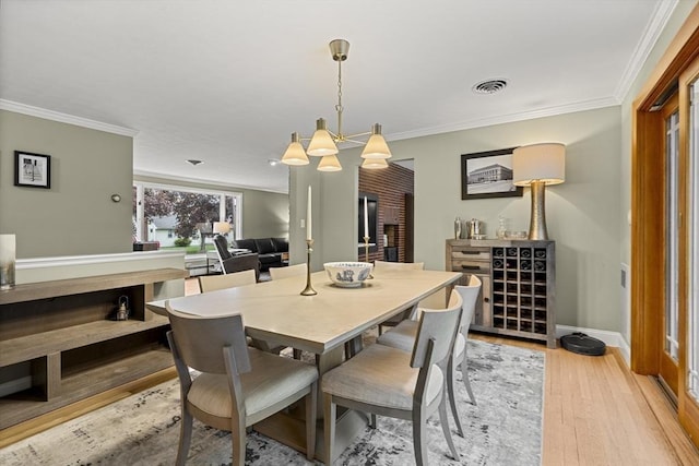 dining space with crown molding, light wood finished floors, a chandelier, and baseboards
