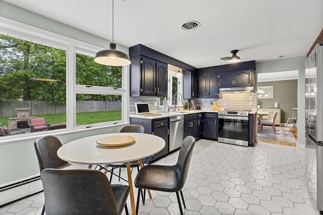 kitchen featuring appliances with stainless steel finishes, under cabinet range hood, a baseboard heating unit, and plenty of natural light