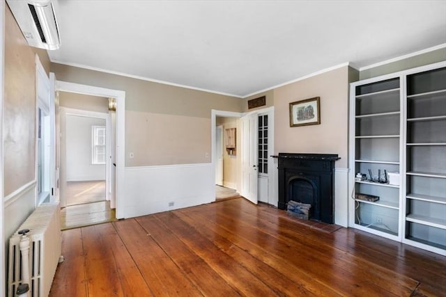 unfurnished living room featuring ornamental molding, radiator, a wall mounted AC, and dark hardwood / wood-style floors