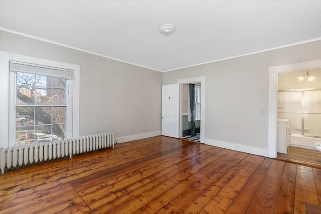 unfurnished room featuring hardwood / wood-style flooring, ornamental molding, radiator heating unit, and an inviting chandelier