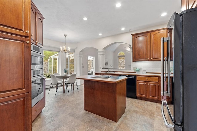 kitchen with black appliances, decorative columns, arched walkways, recessed lighting, and a chandelier