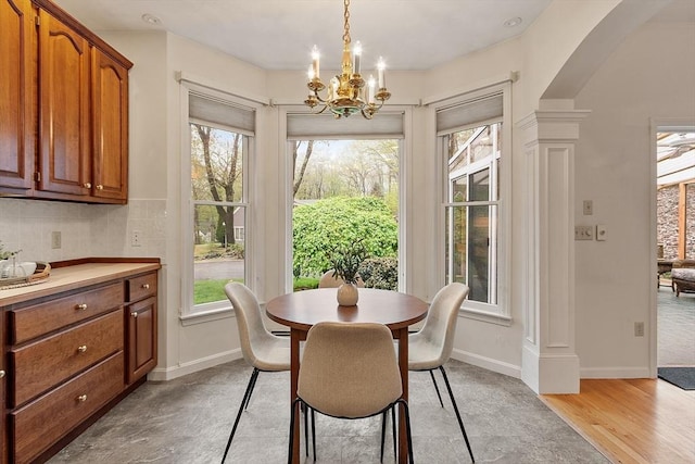 dining room with ornate columns, healthy amount of natural light, a chandelier, and baseboards