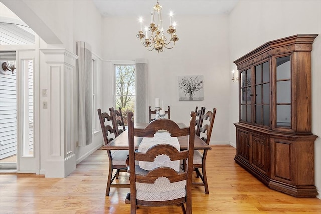 dining room with a high ceiling, a chandelier, light wood-style flooring, and baseboards