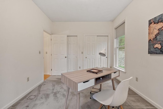 office featuring baseboards and light carpet