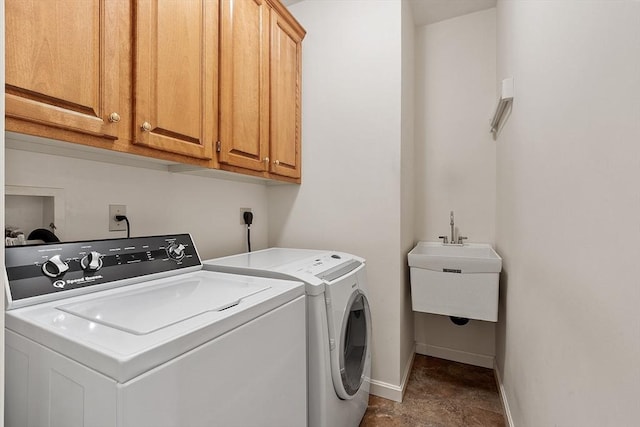 washroom featuring washing machine and clothes dryer, cabinet space, and baseboards
